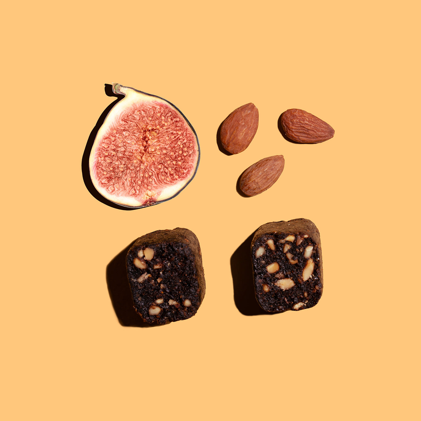 Fichi fig and almond snack bite next to an opened fig and almond.