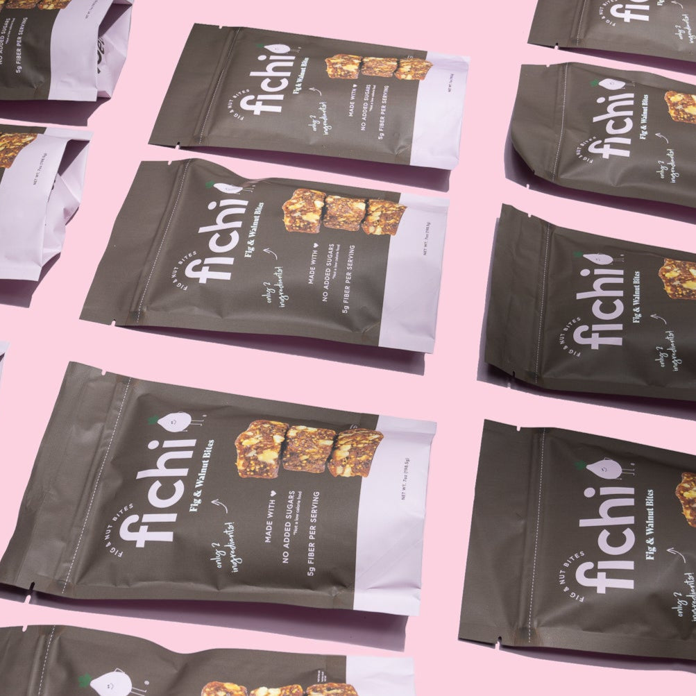 Multiple packages of Fichi
Fig and Walnut snack bites on a pink background.
