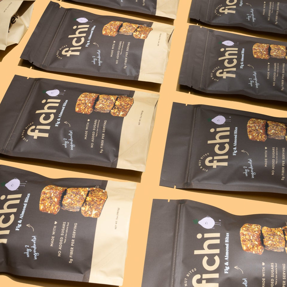 Multiple packages of Fichi Fig and Almond bites on an orange background.