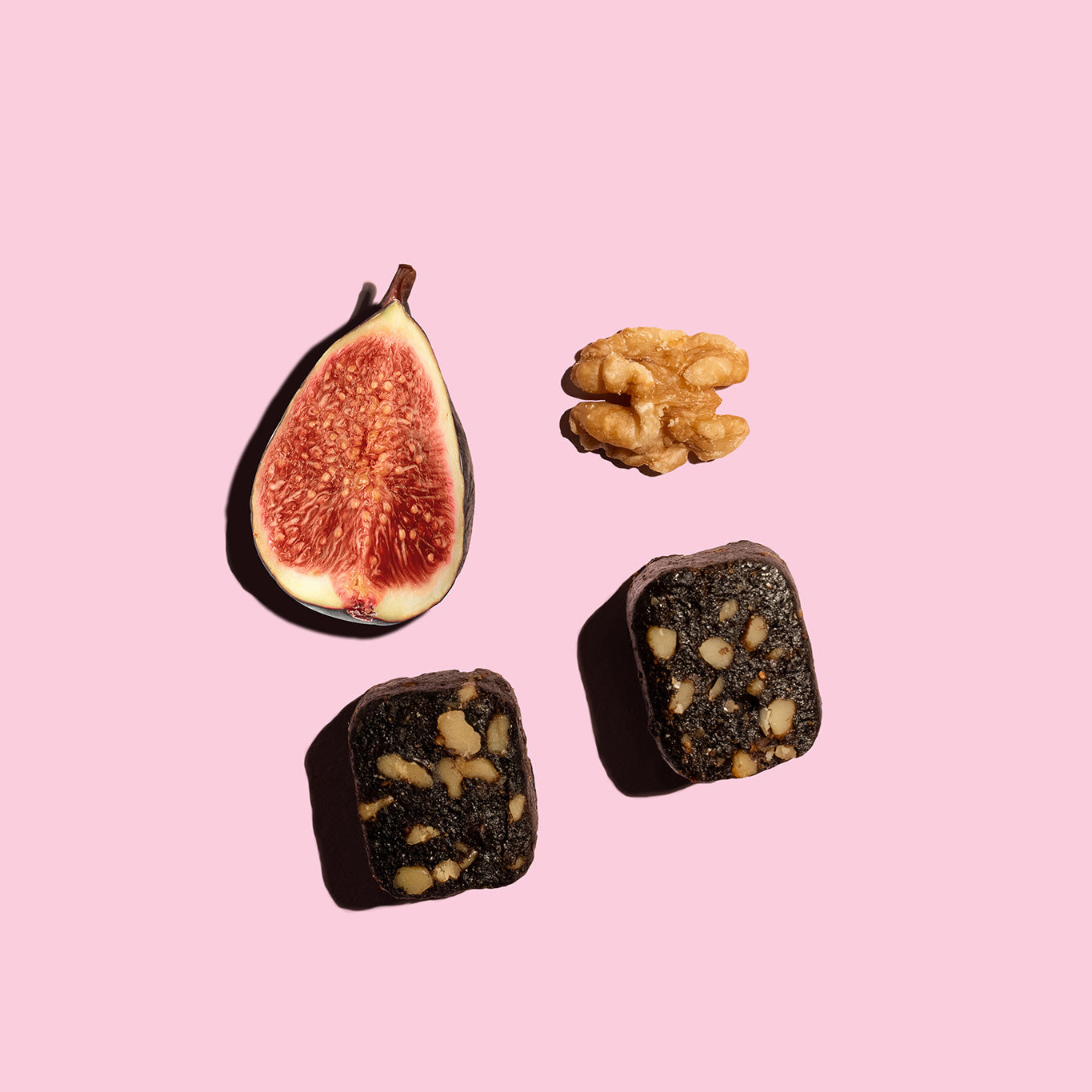 Fichi fig and walnut snack bite next to an opened fig and walnut. 